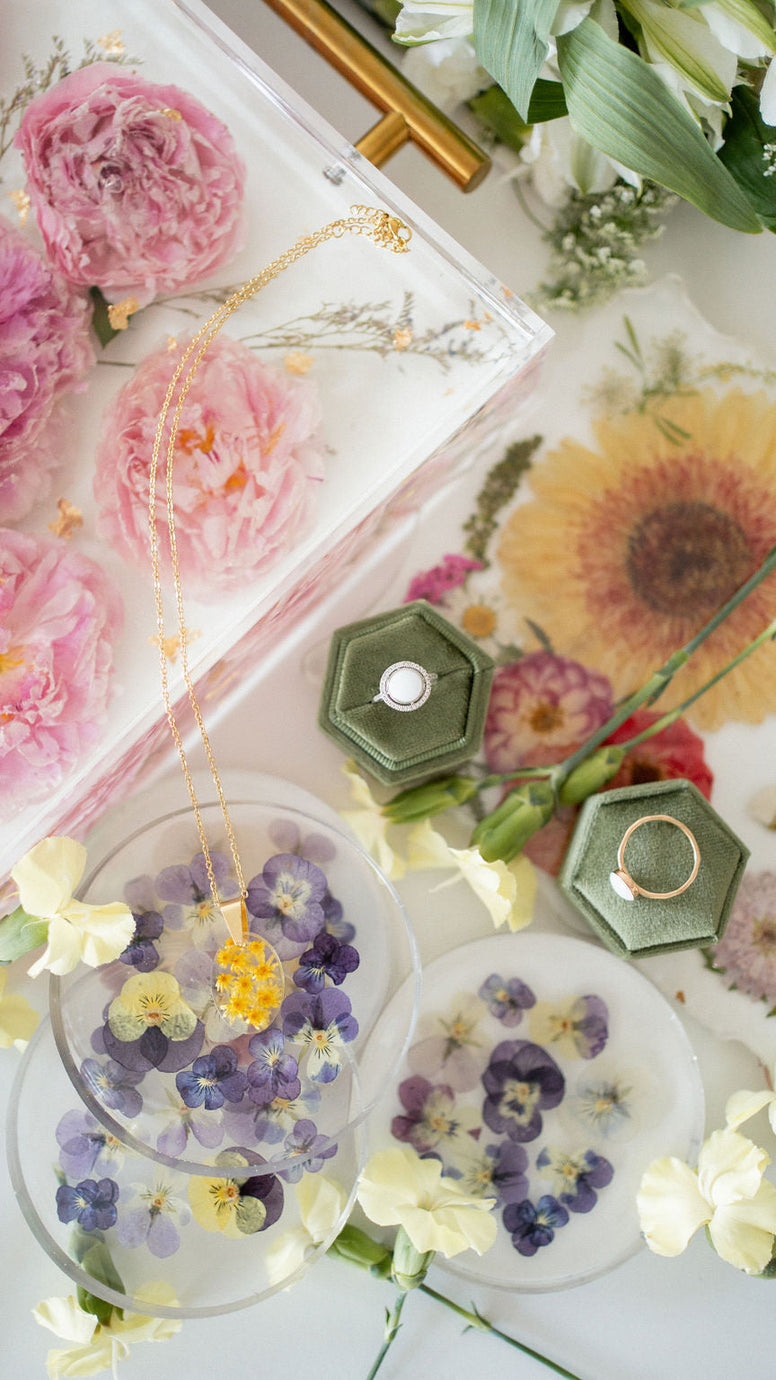 Decorative items with pressed flowers and greenery on a white surface