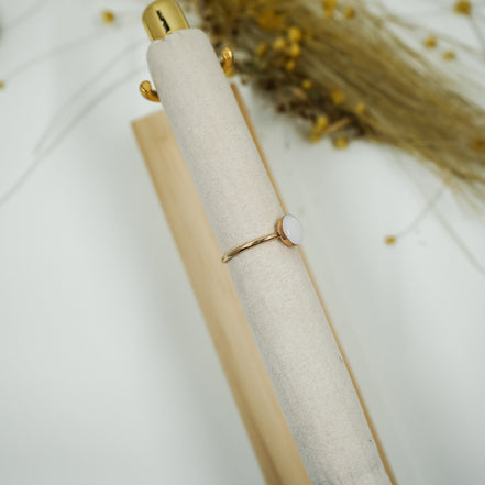 Gold ring on a white fabric surface with a blurred background