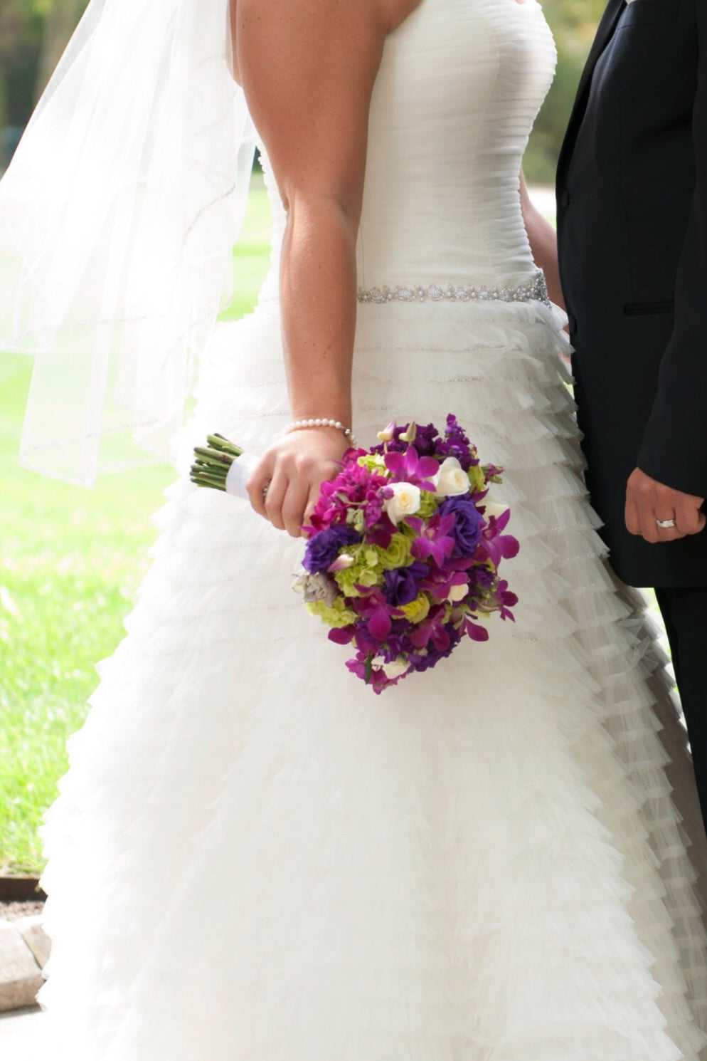 Bride and groom holding hands with a colorful bouquet outdoors.